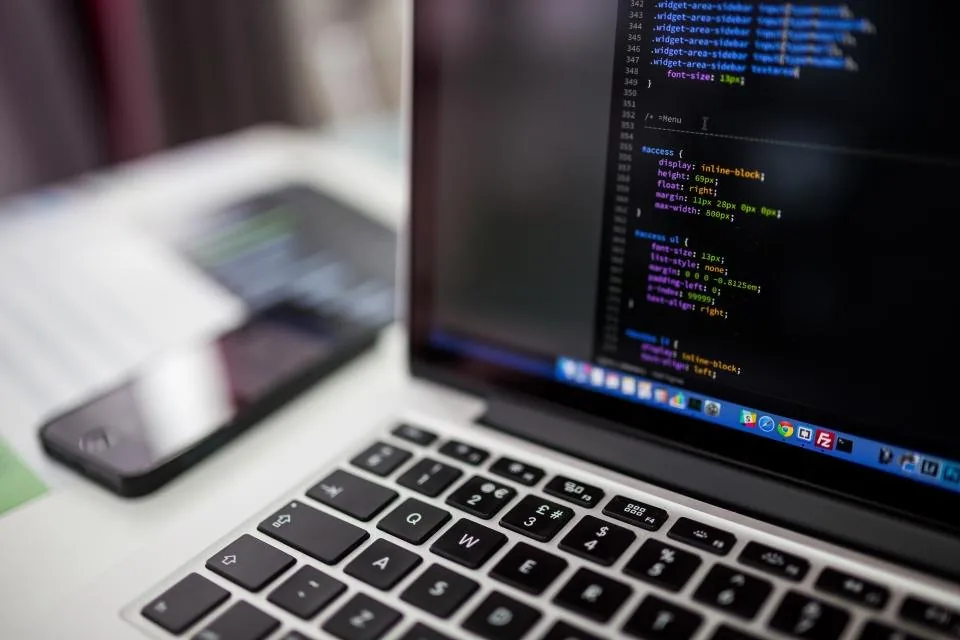 a laptop open on a desk with source code on the screen