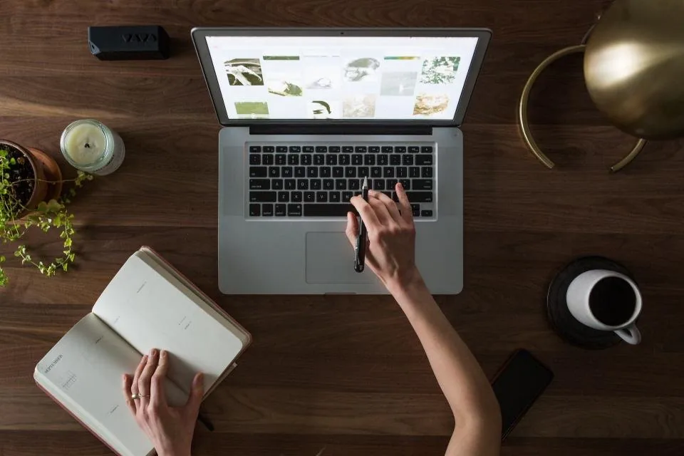 a notebook open on a desk with a pen, a phone and printed sheets beside it