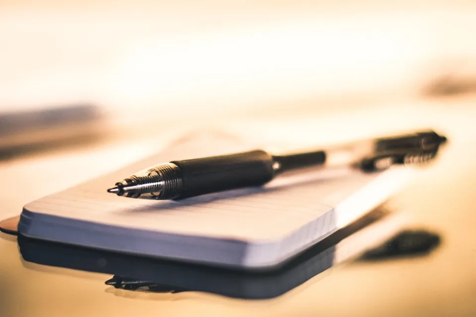 a planner, a notebook and a pen laid out on a desk
