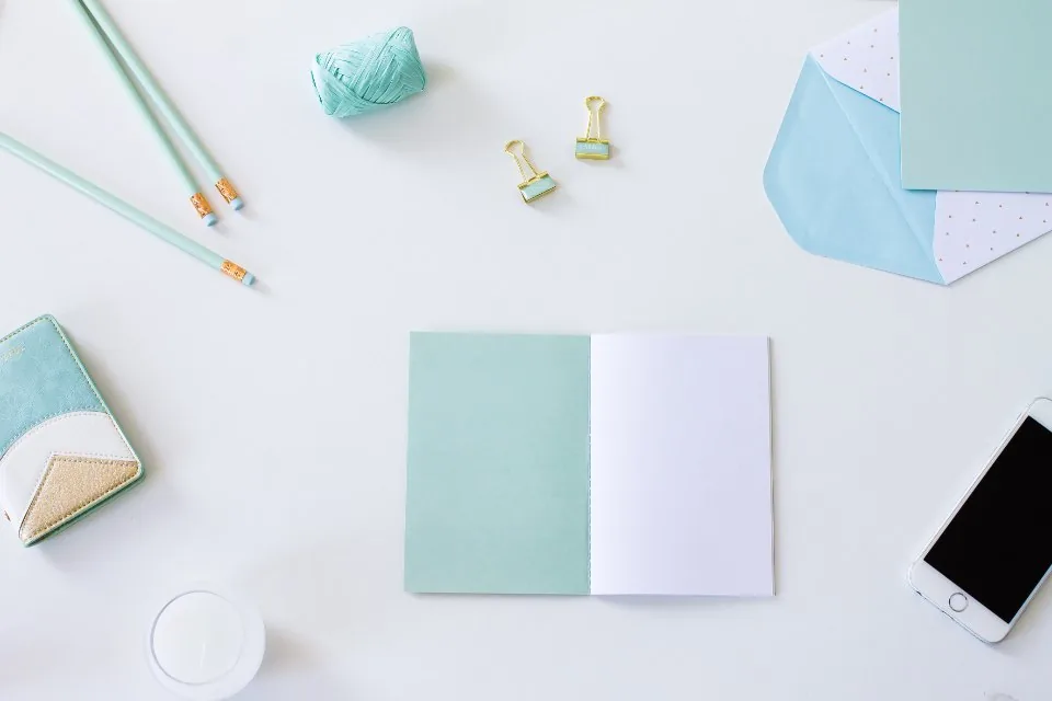 a planner, a notebook and a pen laid out on a desk
