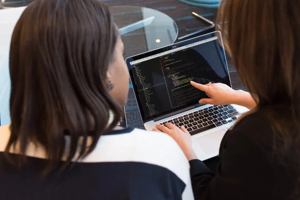 a laptop open on a desk with source code on the screen