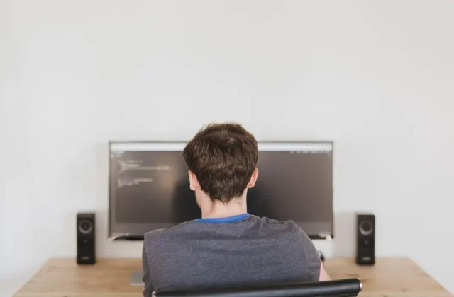 a monitor showing source code with a developer seated at it