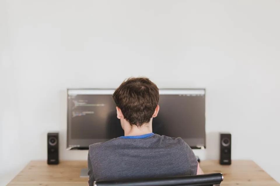 a monitor showing source code with a developer seated at it