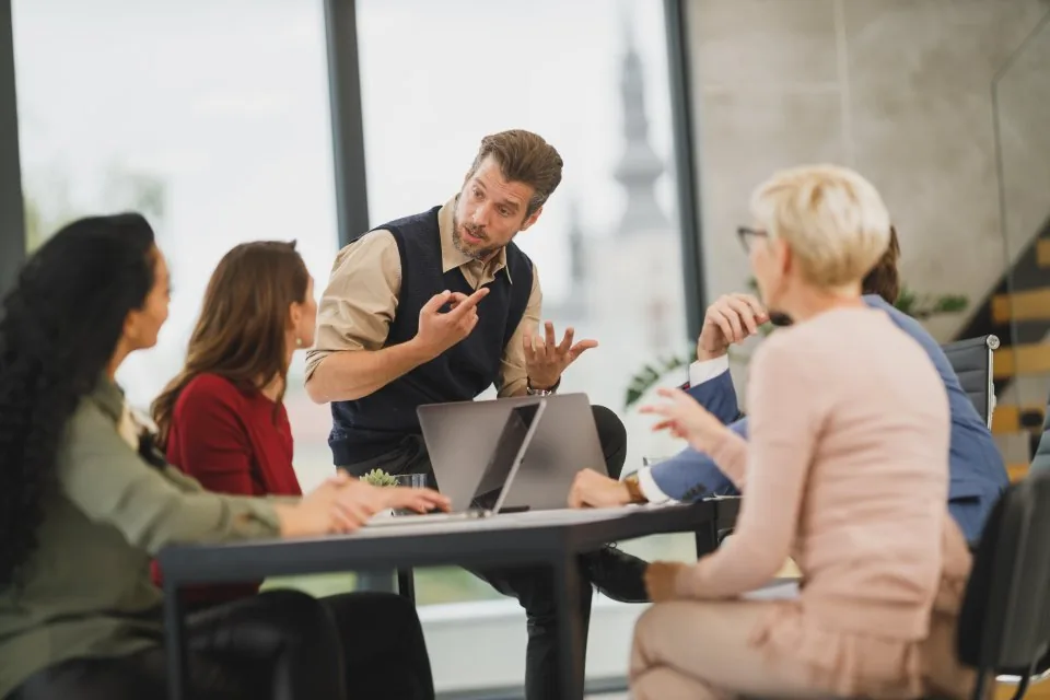 a team working at laptops around a table in a bright office