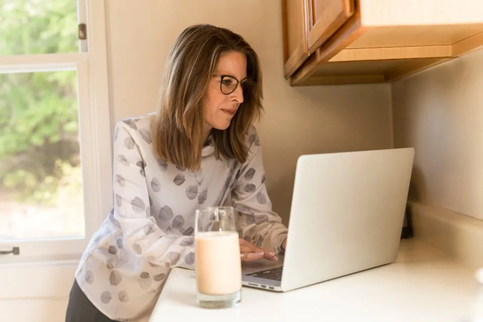 a team working at laptops around a table in a bright office