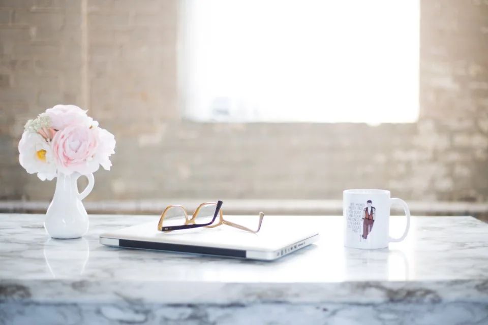 a desk by a window with a laptop open in daylight