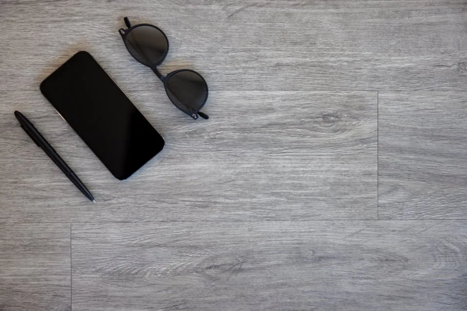 a close view of a desk with a keyboard, a notebook, a pen and a coffee cup