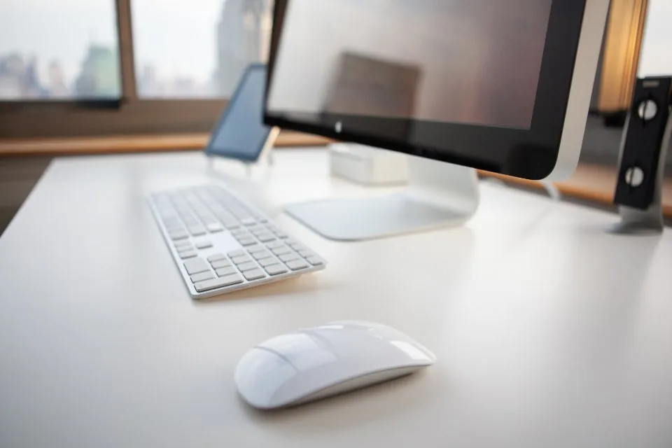 a close view of a desk with a keyboard, a notebook, a pen and a coffee cup