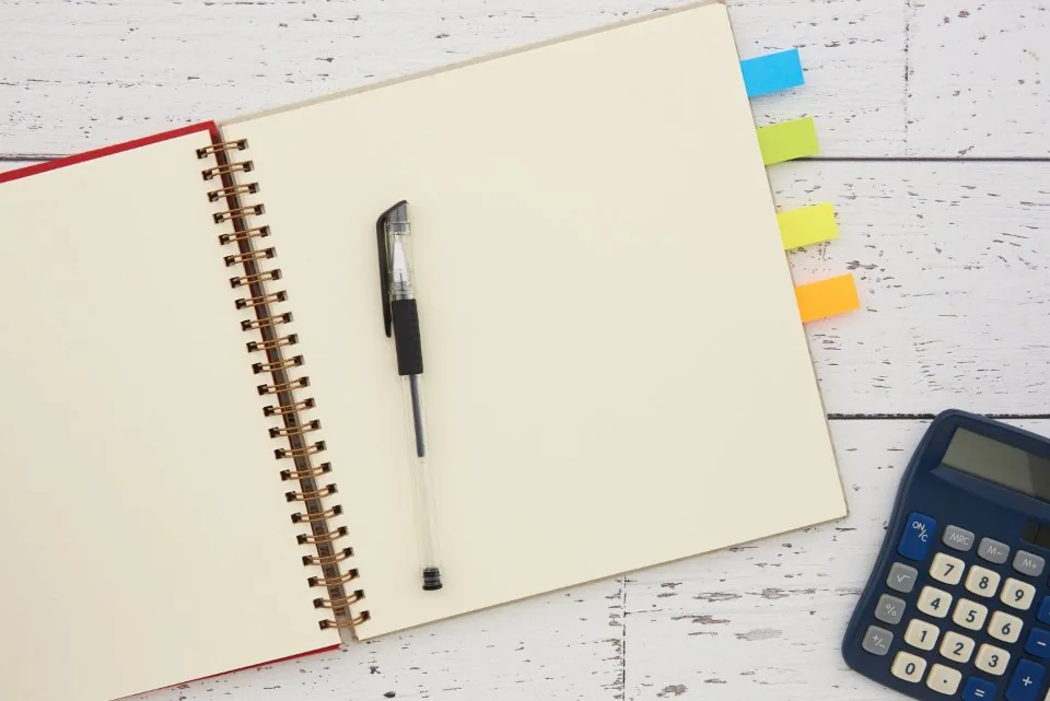 a calculator, a phone and printed financial papers on a desk
