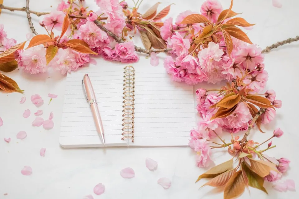 a planner, a notebook and a pen laid out on a desk