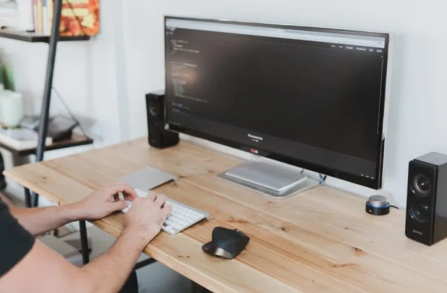 a monitor showing source code with a developer seated at it