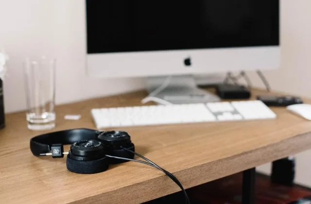 a desk with a laptop, a headset and a phone arranged for calls
