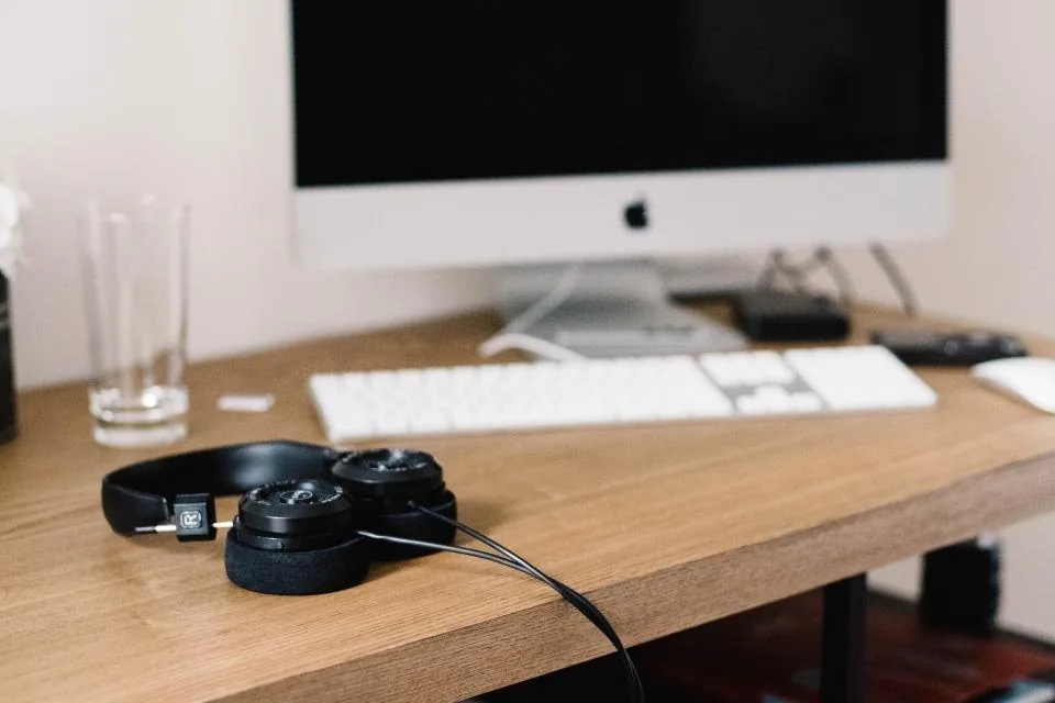 a desk with a laptop, a headset and a phone arranged for calls