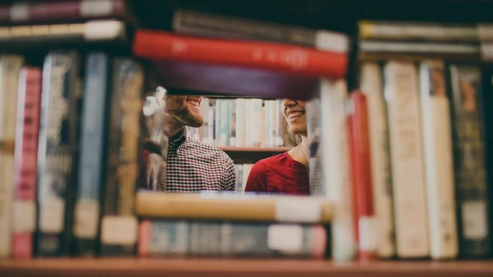 shelves of books in a library with a desk and a laptop in front of them