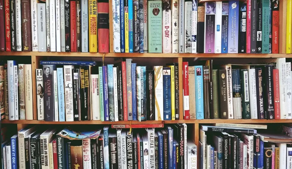 shelves of books in a library with a desk and a laptop in front of them