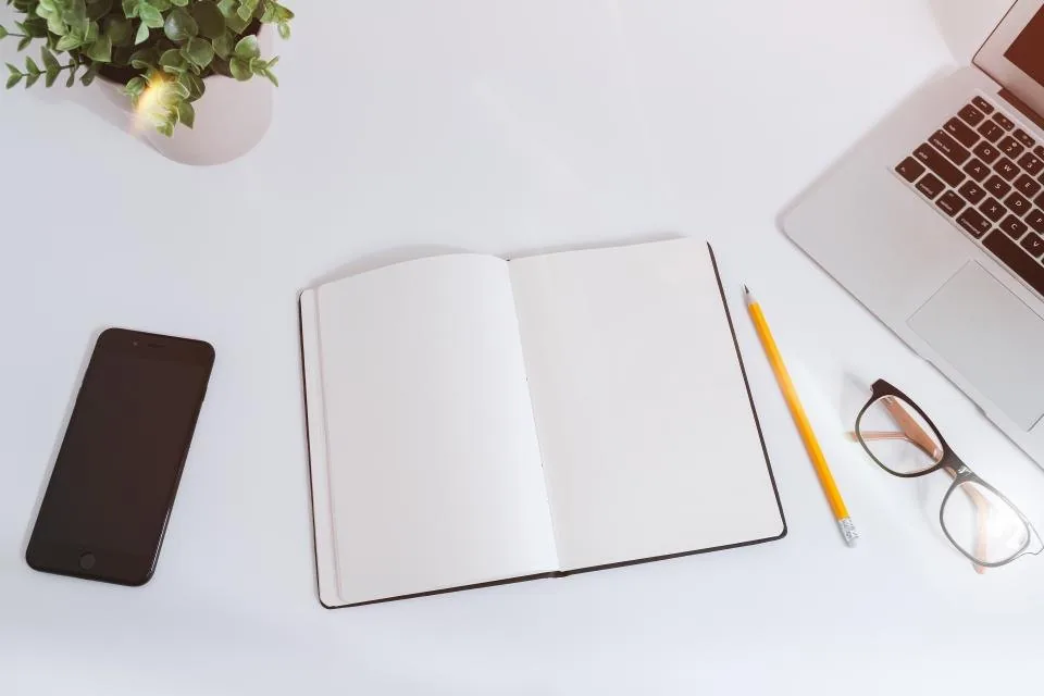 a spiral notebook and pen laid out on a wooden desk