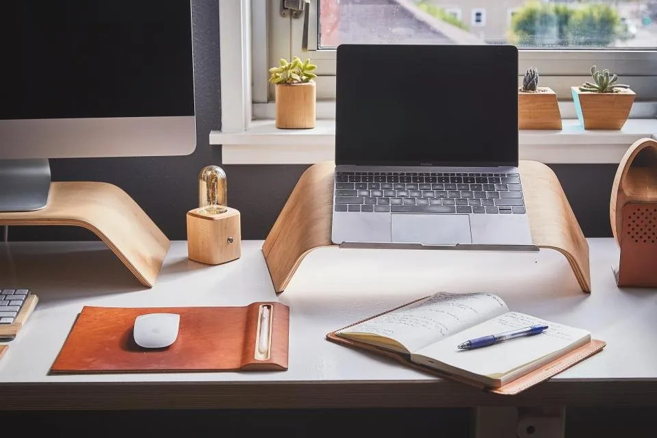 a spiral notebook and pen laid out on a wooden desk