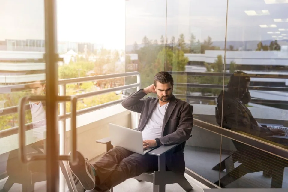 a team working at laptops around a table in a bright office