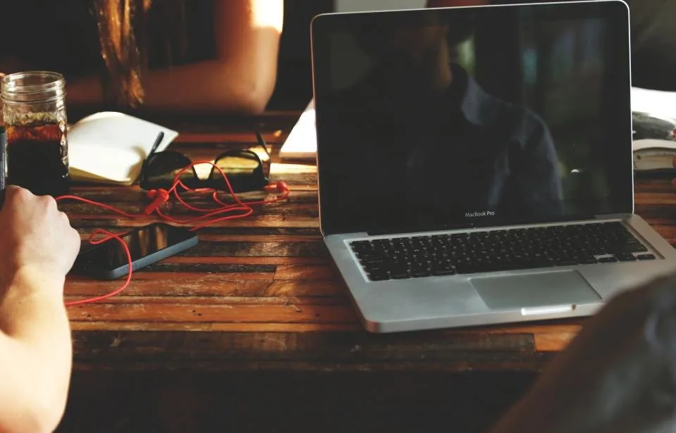 hands working together over a laptop and notes at a table