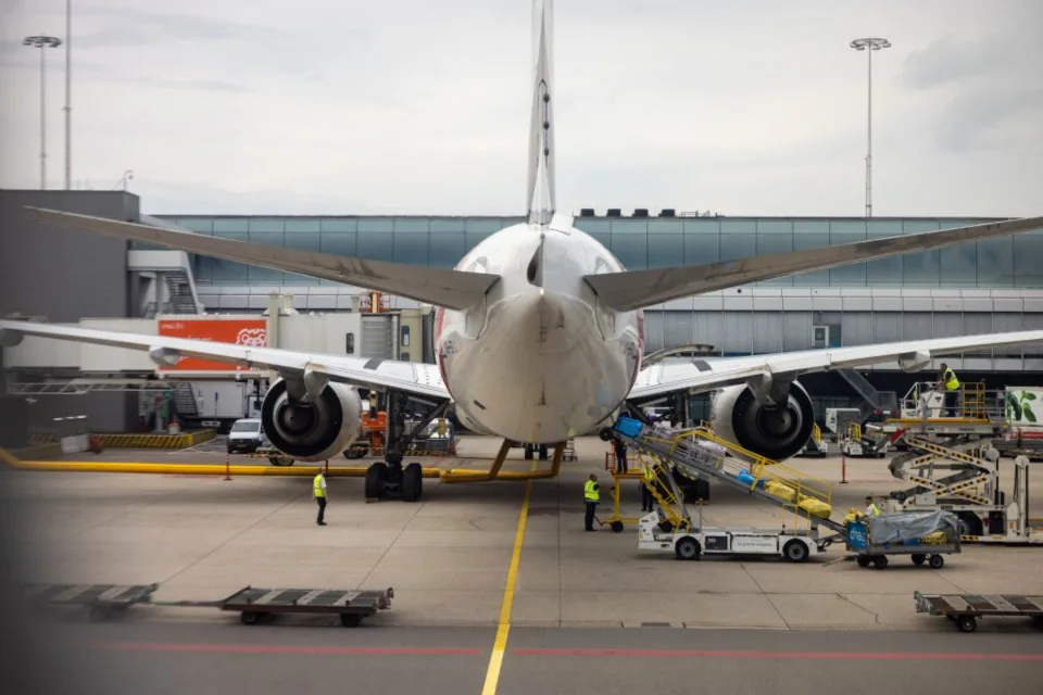 an airport apron and terminal with aircraft and travellers