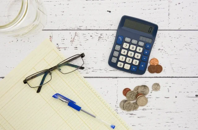 a calculator, a phone and printed financial papers on a desk