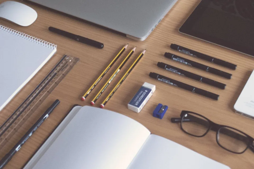 a planner, a notebook and a pen laid out on a desk