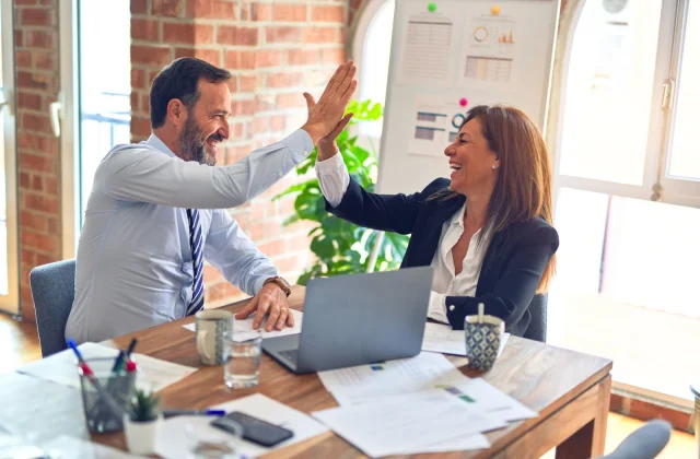 Two colleagues celebrating the end of a piece of work in an office.
