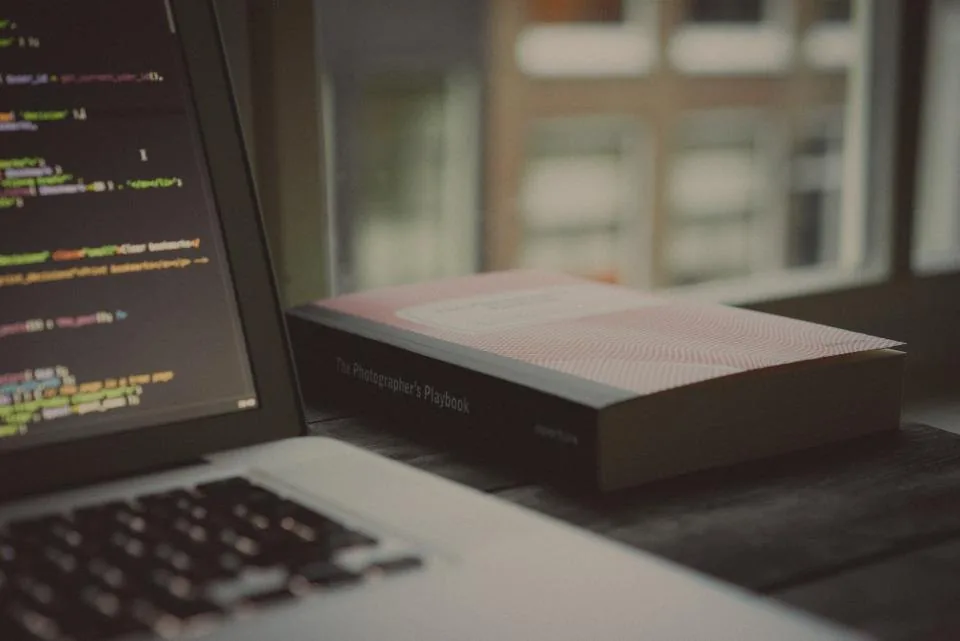 a laptop open on a desk with source code on the screen