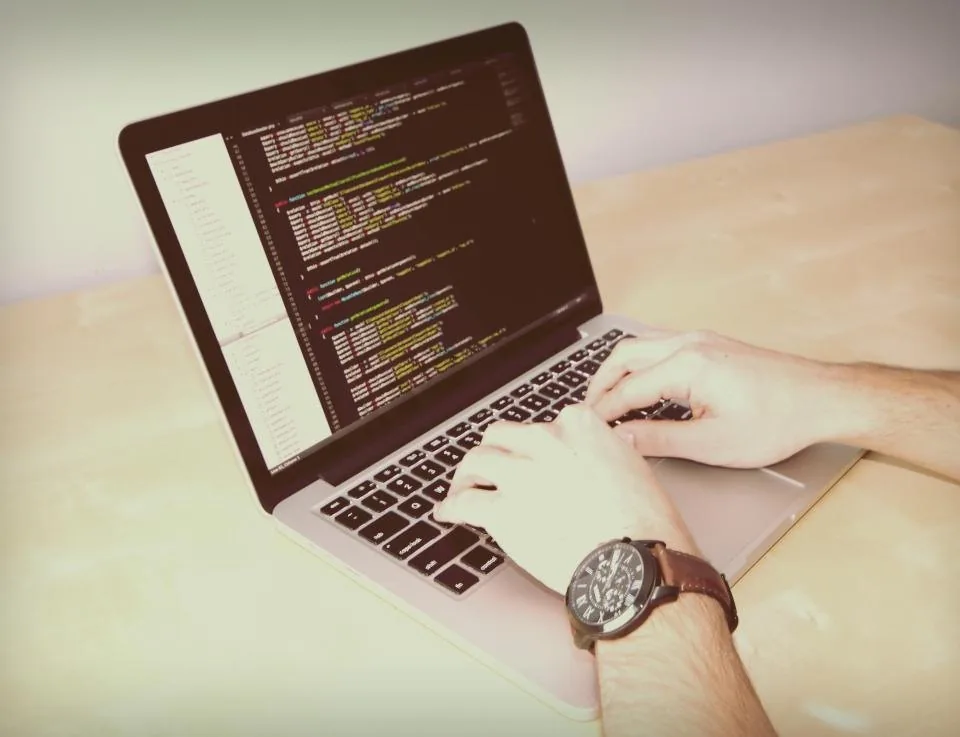 a laptop open on a desk with source code on the screen