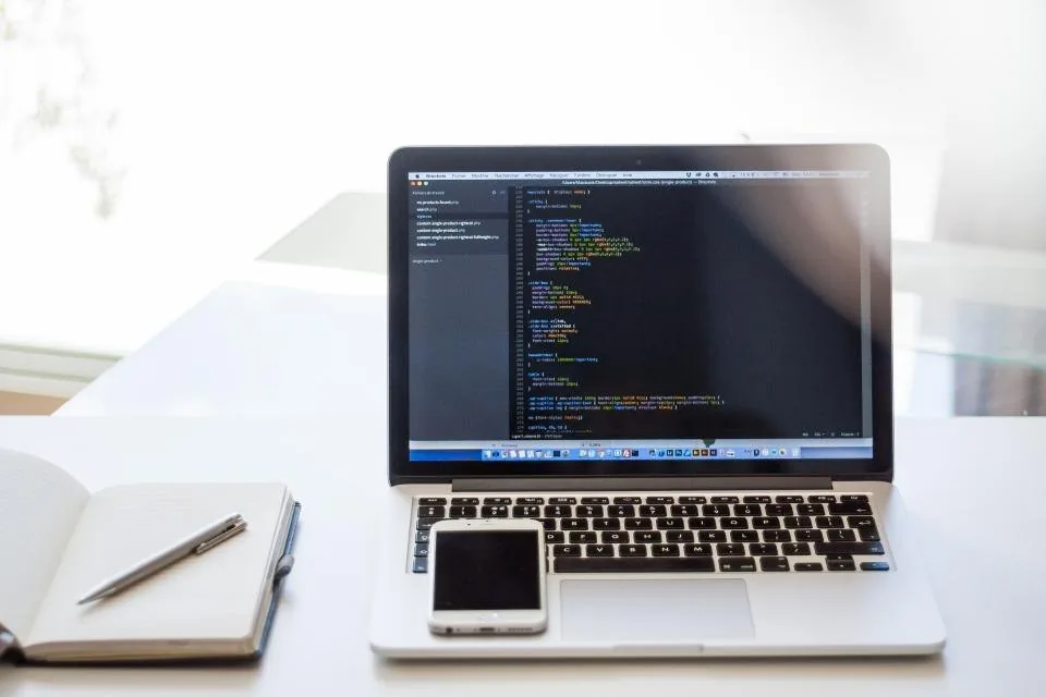 a laptop open on a desk with source code on the screen
