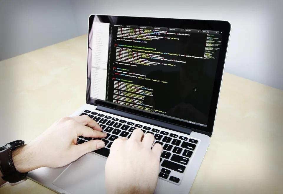 a laptop open on a desk with source code on the screen