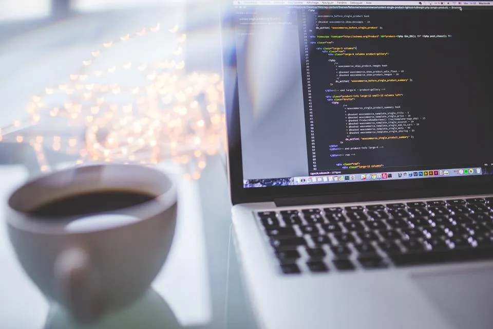a laptop open on a desk with source code on the screen