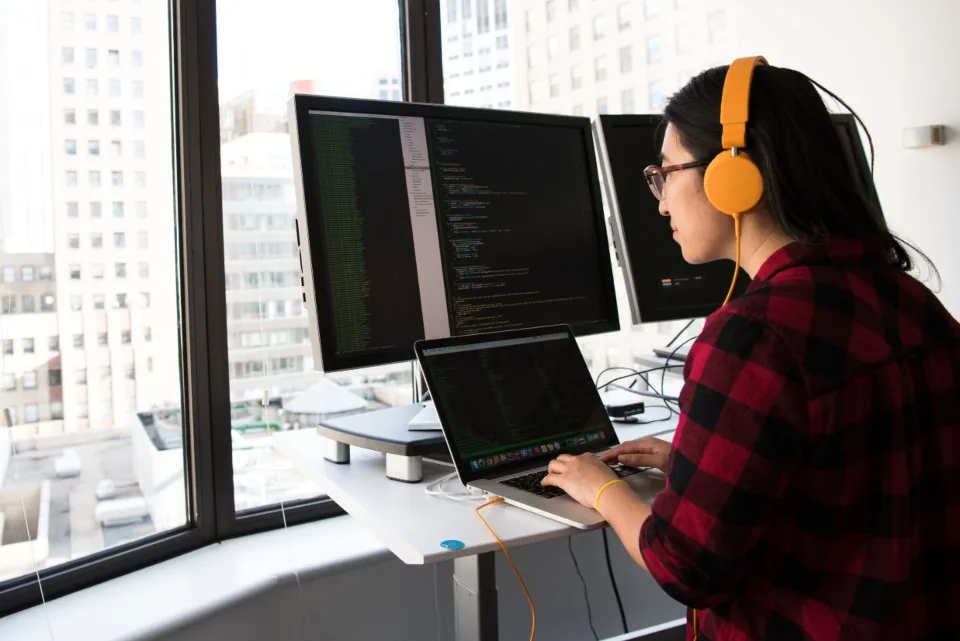 a monitor showing source code with a developer seated at it