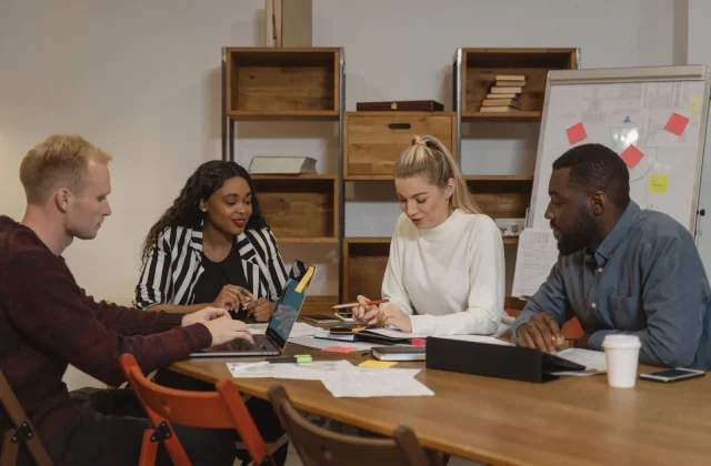 A group of colleagues working through a project together around a table in an office.