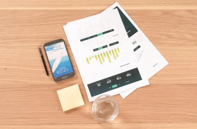 printed documents, a clipboard and a pen spread across a desk