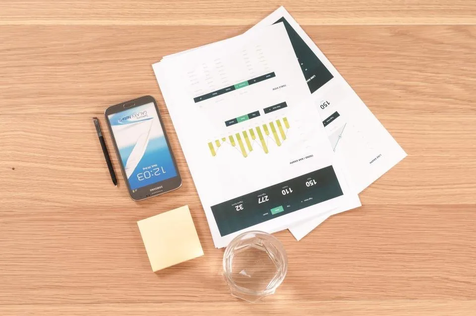 printed documents, a clipboard and a pen spread across a desk
