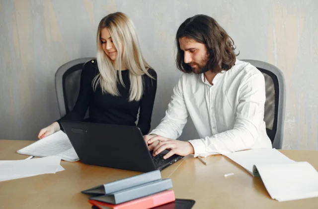 Two colleagues working side by side on a shared task in a modern office.