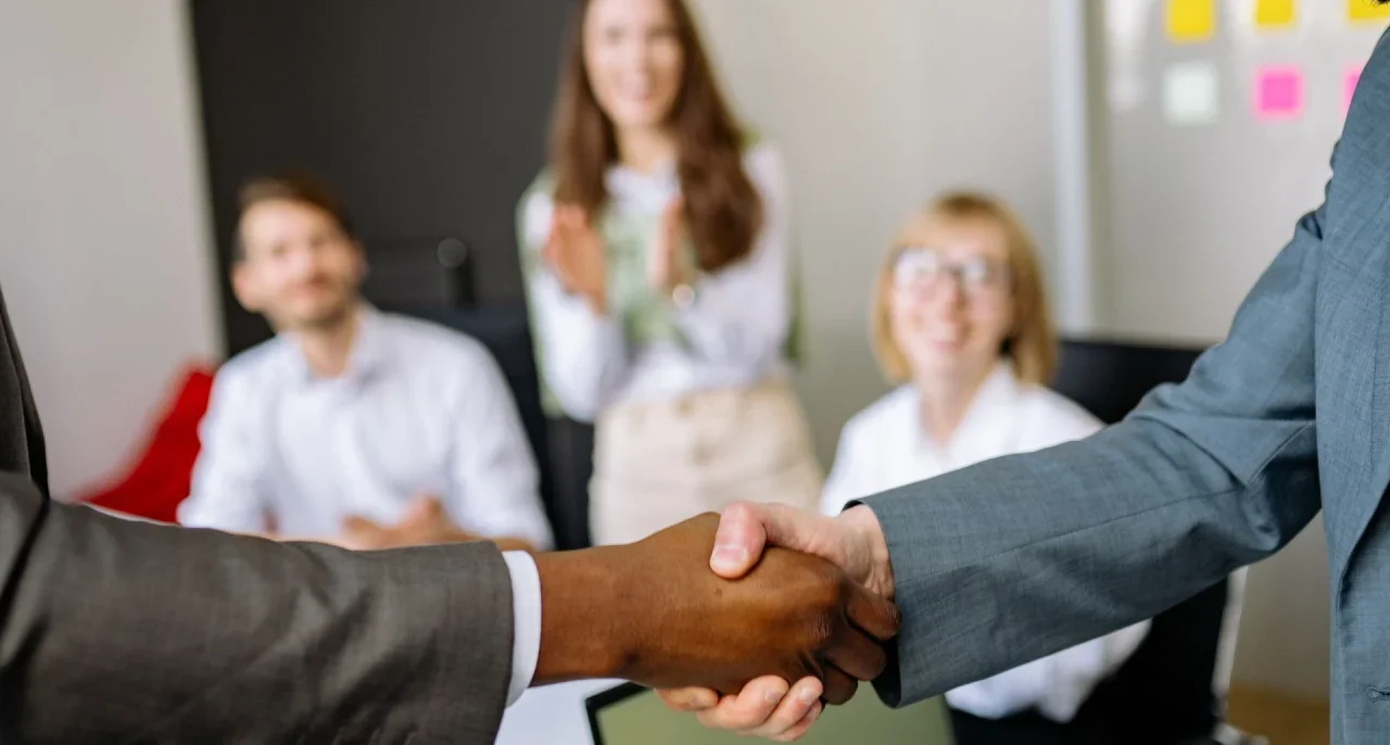 Two colleagues shaking hands at the end of a project in an office.