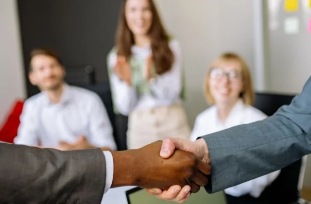 Two colleagues shaking hands at the end of a project in an office.