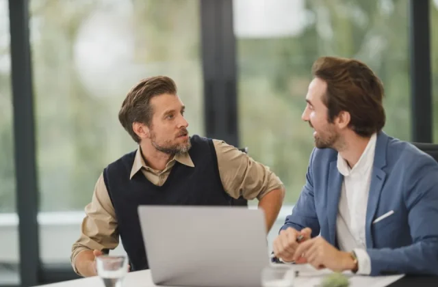 colleagues in discussion around a table with laptops open