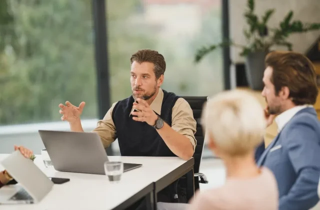 a team working at laptops around a table in a bright office