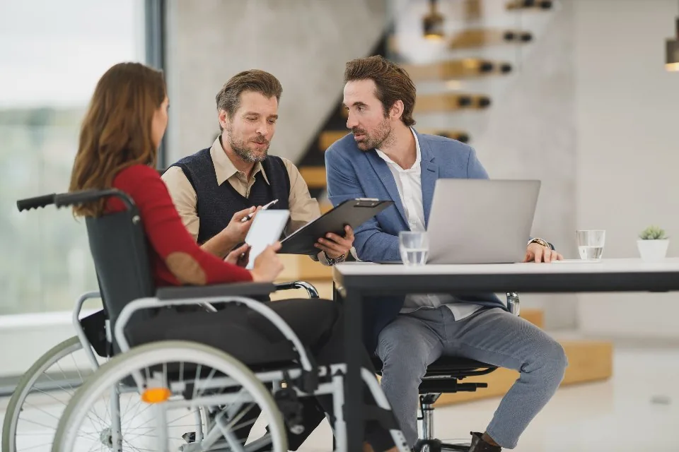 a team working at laptops around a table in a bright office