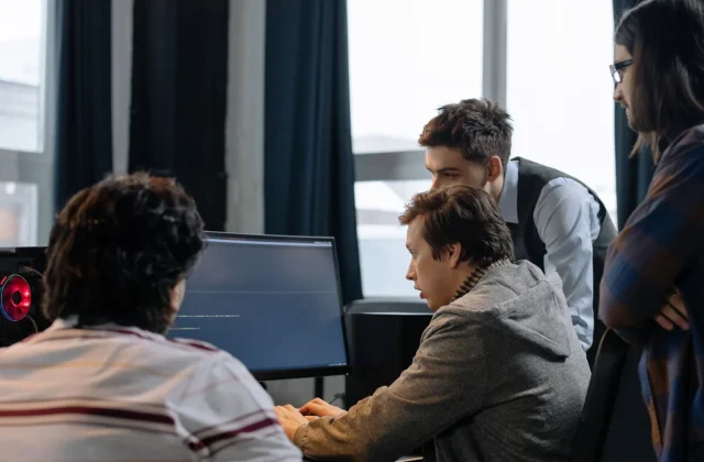 A group of developers working together on a software project at one desk.