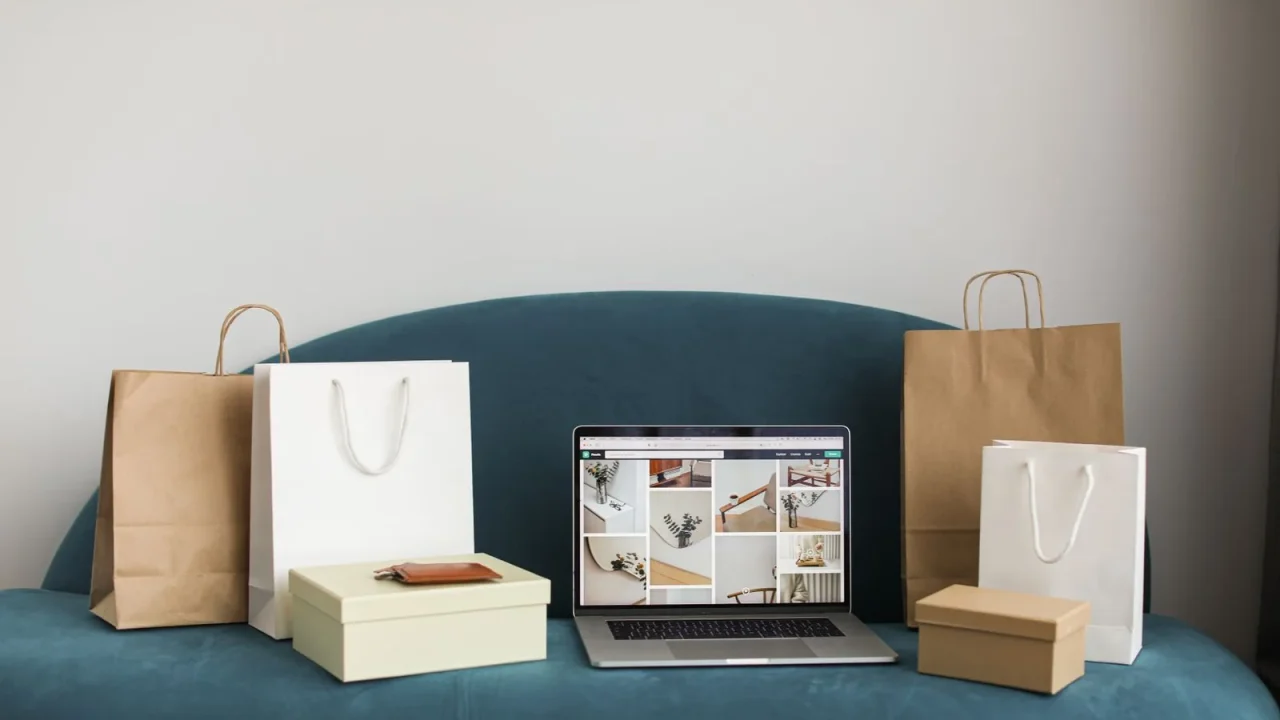 Laptop displaying an online store beside delivery packaging on a sofa.