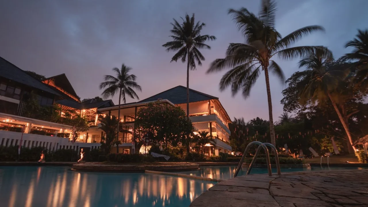 Resort swimming pool and palm trees at dusk.