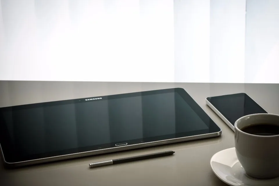 a tablet held and used at a desk beside a keyboard