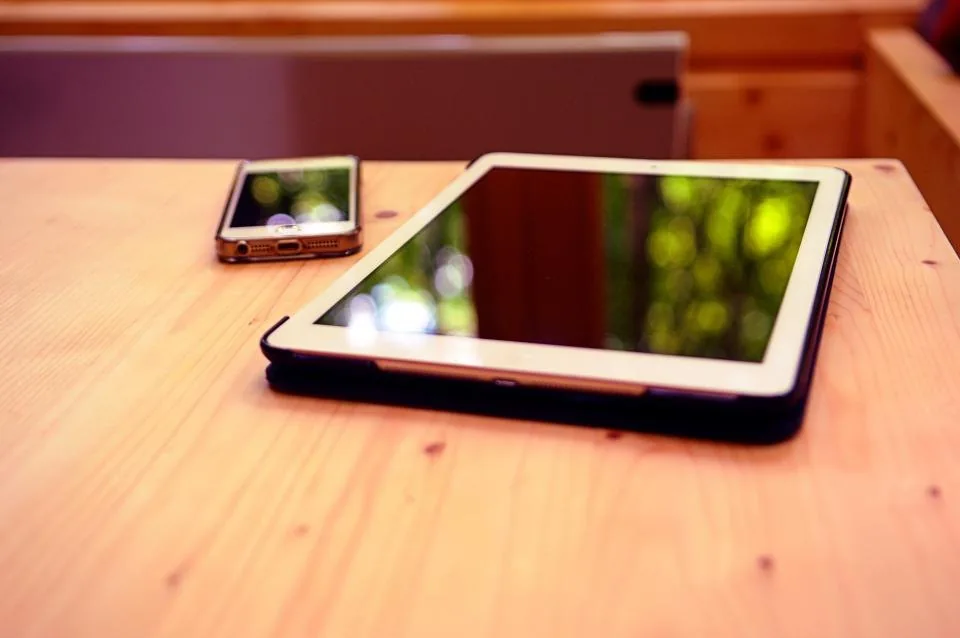 a tablet held and used at a desk beside a keyboard