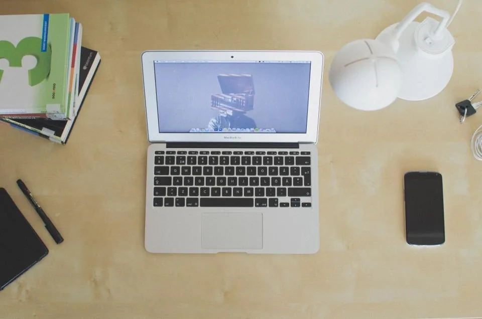 a desk by a window with a laptop open in daylight