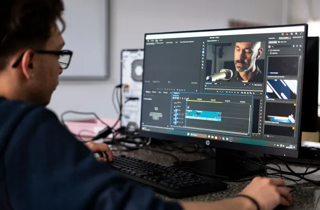 An editor cutting footage at a desktop computer in an office.