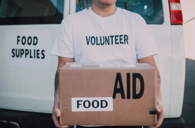 A volunteer holding a box of food aid ready to hand over.